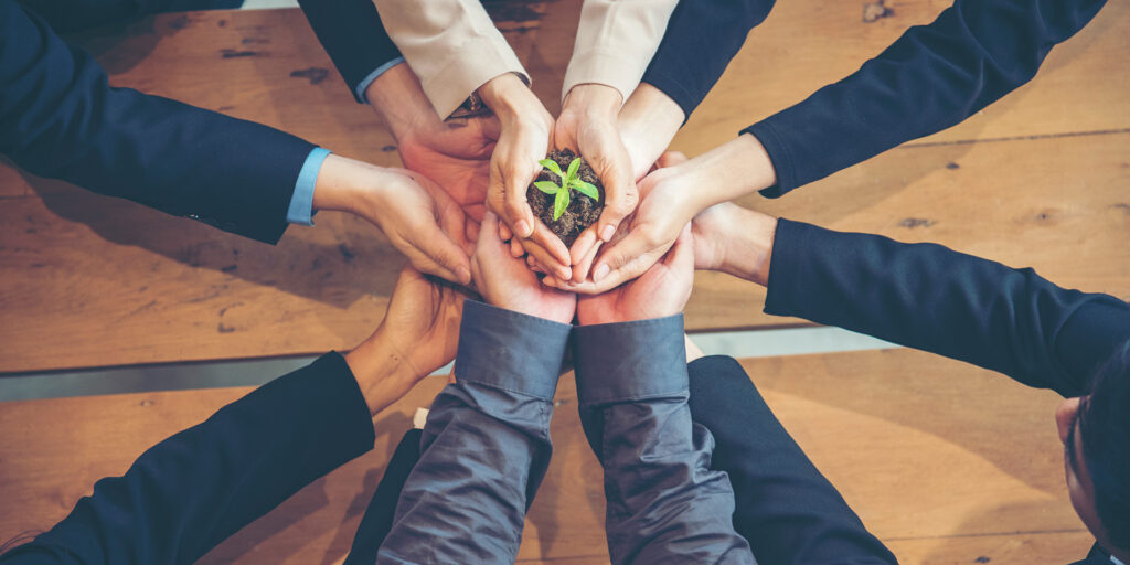 Une image symbolique de l'investissement à impact social, telle qu'une main tenant une plante en croissance, représentant la croissance durable et l'engagement social.