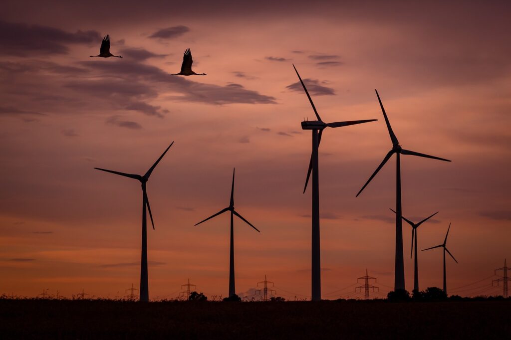 Une photo d'un parc éolien avec des éoliennes en fonctionnement, prise au coucher du soleil.